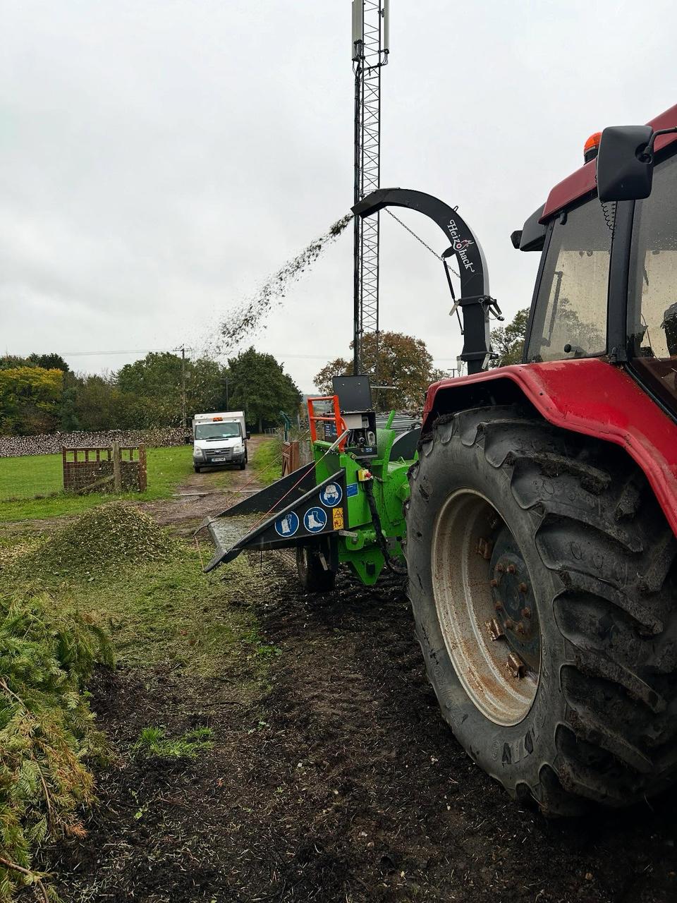 Tractor-powered wood chipper processing timber